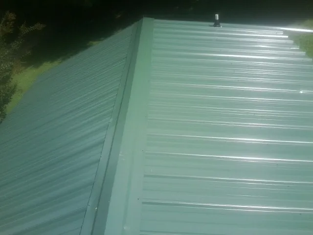 New green metal panels meeting at the ridge of a roof — Flat Roof Repair work by our crew in West Memphis