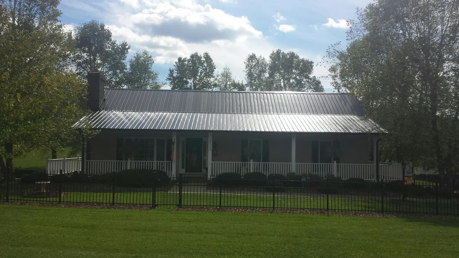 Gray metal roof on a brick ranch with a full width front porch — Gutter Guard Installation work by our crew in West Memphis
