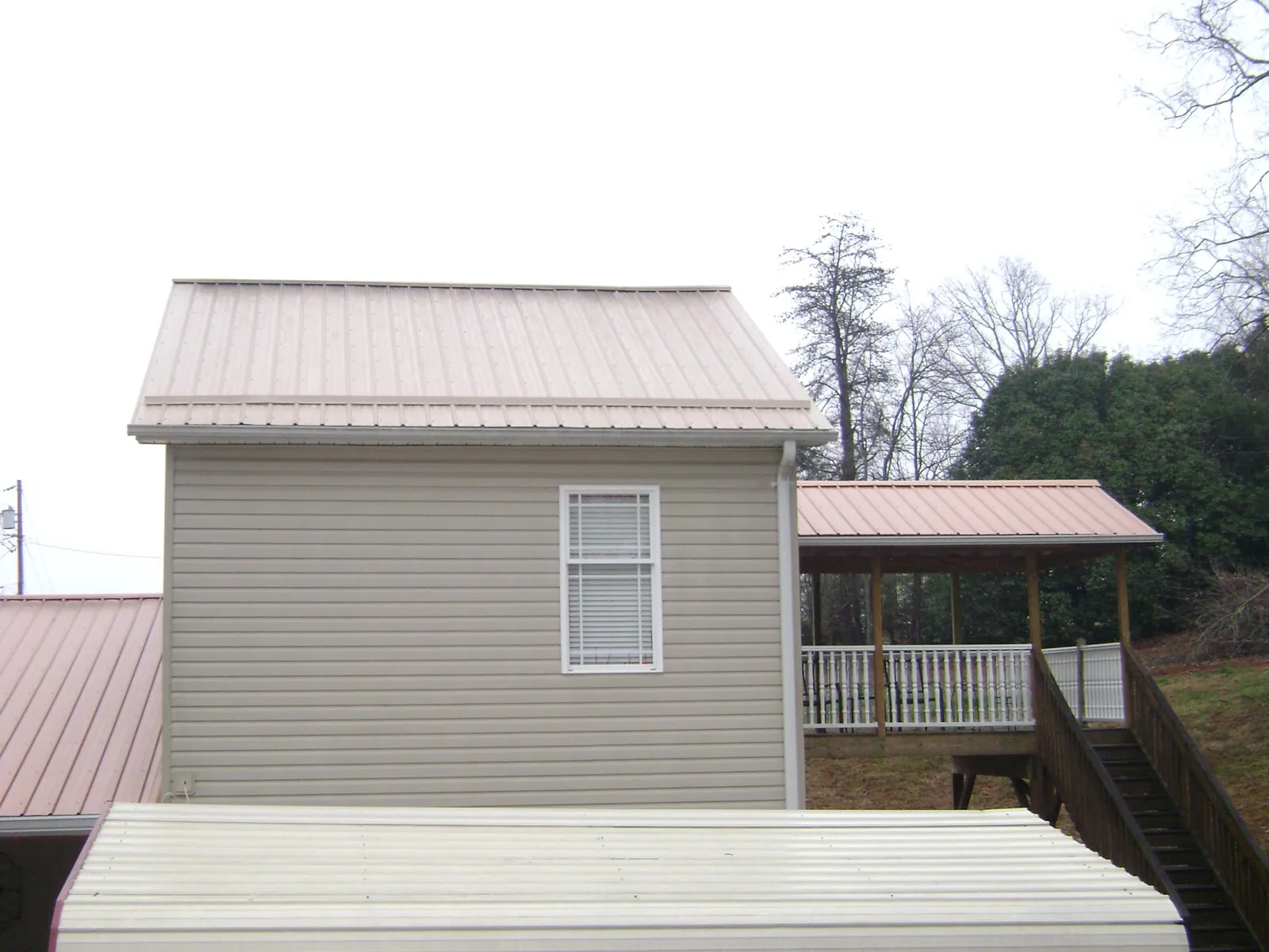Tan metal roofs on a two story addition and attached porch, from a Roof Replacement job in West Memphis