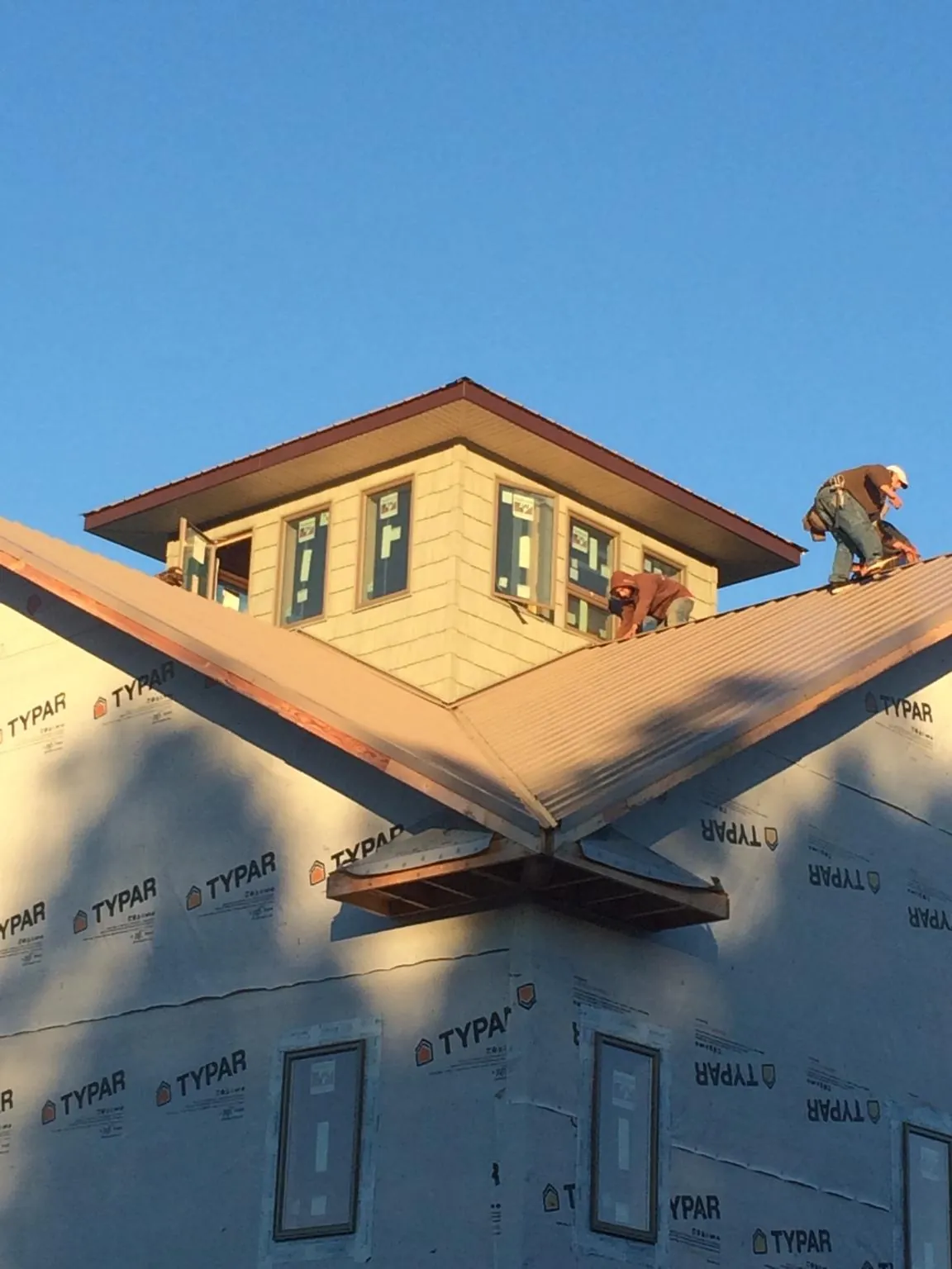 Roofers working around a rooftop cupola on a new metal roof at sunset — Roof Waterproofing in West Memphis by Roofing Brothers